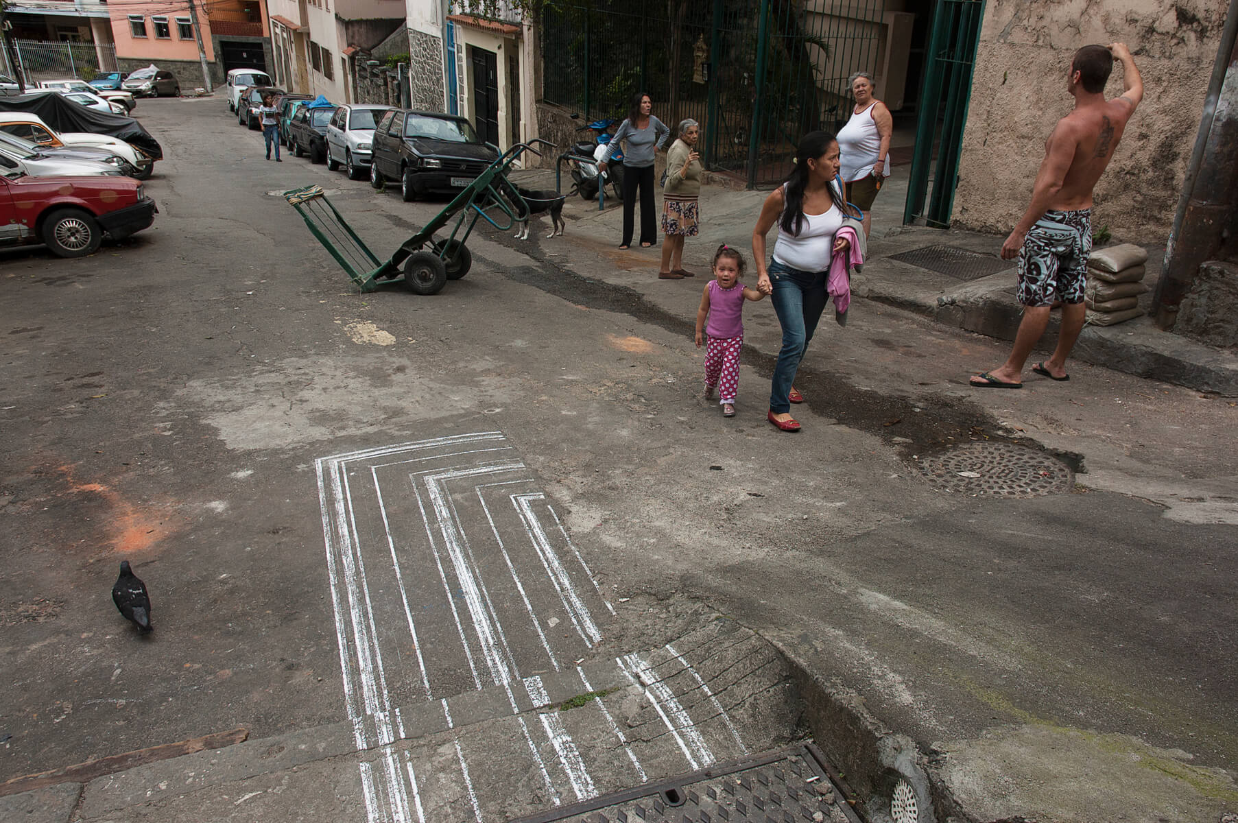 Chalk linedrawing on an also messy backstreet with people, a dog, a pigeon and a handcart in the middle of the street